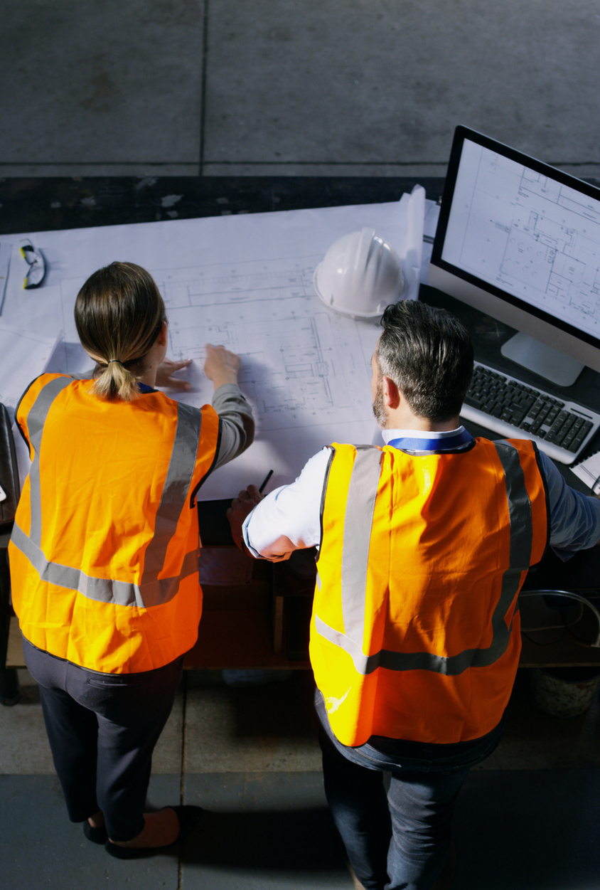High angle shot of two engineers going over a blueprint together in an industrial place of work