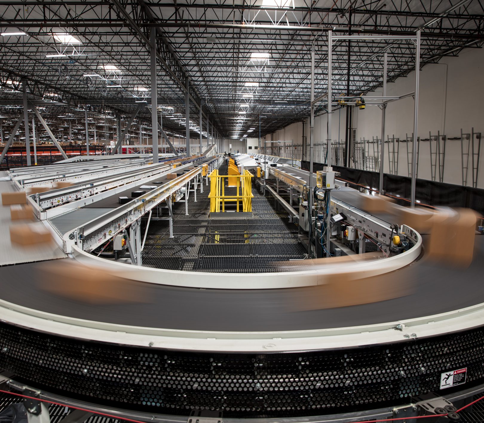 Packages blur as they rush past on the complex conveyor belt system that sorts them for delivery at a large fulfillment center.